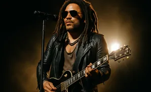 Lenny Kravitz performs on stage, playing an electric guitar and singing into a microphone.
