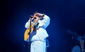 lewis capaldi singing with guitar in white outfit