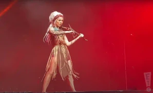 lindsey stirling plays the violin on stage under red lights