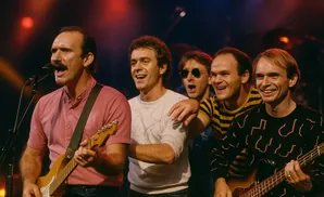 A band of five men on stage playing guitars and singing, with the lead singer in front.