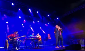 michel fugain singing on stage in dark clothing