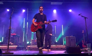 noah kahan playing live on stage in front of purple lights