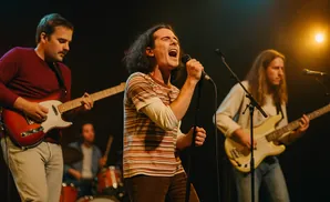 A band performs on stage, with a singer in the foreground and guitarists and drummer in the background.