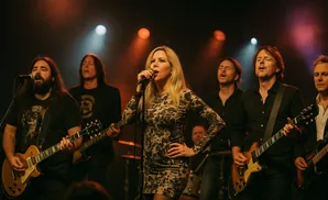A band performs on stage with a female singer at the microphone and male guitarists.