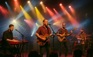 Band performing on stage with colorful lights, a keyboardist, two guitarists, and a drummer.