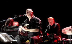 swans lead singer singing while playing the guitar