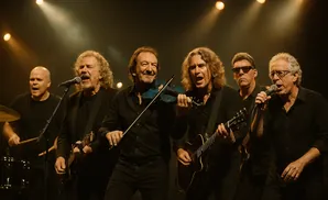 Band members performing on stage with instruments under spotlights.