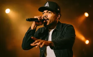 Chance the Rapper performs wearing a denim jacket and a black cap.