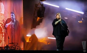 jelly roll performing on stage in a black shirt holding the microphone