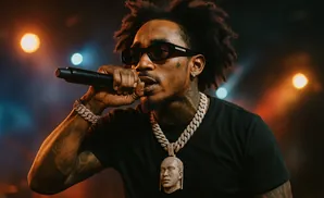 Rapper in sunglasses and chains holding a microphone on stage