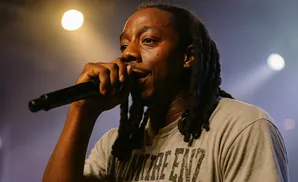 Rapper speaks into a microphone while wearing a blue and yellow jersey with the number 22.