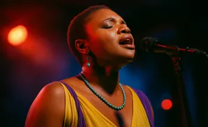 Woman with her back to the camera, wearing a white dress and elaborate updo, stands before a blurred audience in a theater.