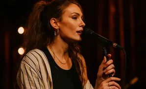 Singer performing into a microphone, with bokeh lights in the background.