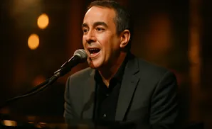 Man in a dark suit singing into a microphone