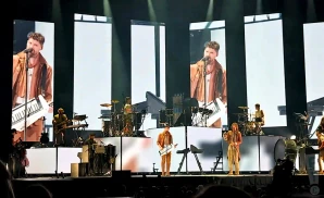 a rear view picture of the band for king and country  performing on stage to a large audience 