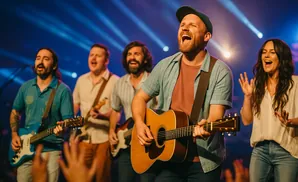 A band plays on stage with bright blue and white lights behind them.