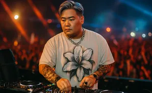 DJ performing on stage with colorful lights and a blurred crowd in the background.