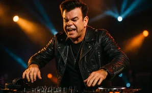 DJ in a leather jacket performing, with colorful stage lights in the background.