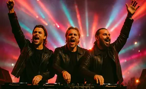 Three DJs in leather jackets at turntables with arms raised and mouths open.