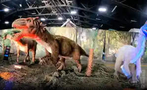 dinosaur statues in front of a forest backdrop at jurassic quest.