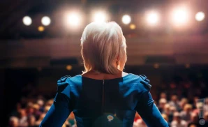 a realistic photograph from behind american medium theresa caputo, performing on stage in front of a large audience.