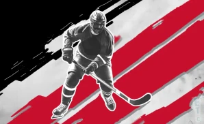 a red river spartans ice hockey player about to hit the puck