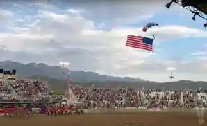 parachuter flying through the air with american flag at the ute stampede rodeo.