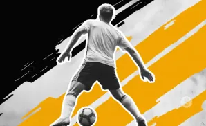 A soccer player in mid-stride, with a ball at his feet, against a black and yellow abstract background.