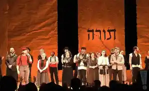 fiddler on the roof cast standing together at curtain call.