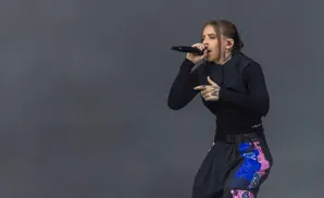 Rapper performing on stage in black outfit with colorful pants.