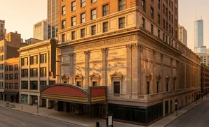 An ornate, vintage theater facade illuminated by golden hour light in a city street.