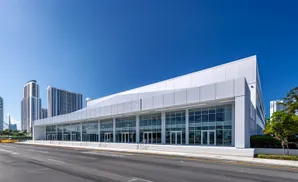 Modern convention center with large glass facade and white exterior, set against a clear blue sky.