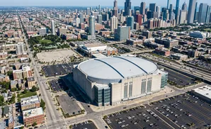 Aerial view of United Center stadium in Chicago with surrounding city skyline and highways.