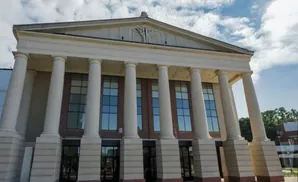 Front view of a large building with classical architecture, featuring tall white columns and a triangular pediment.