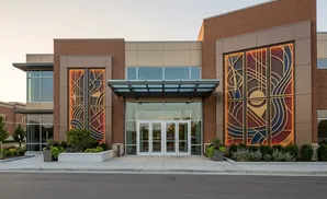 Modern building entrance with large stained-glass windows and glass doors.