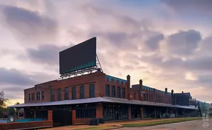 Brick building with a large billboard against a cloudy sky.