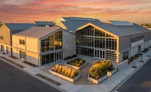 Modern building with metal roof and large windows at sunset.