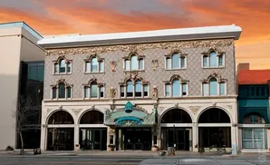 Exterior of an ornate historic building with arched windows and decorative facade, under a vibrant sunset sky.