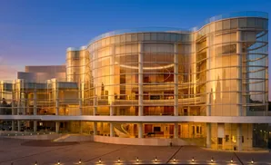 A modern glass building with a curved facade reflecting the warm glow of sunset.