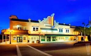 A theater building at dusk with illuminated marquee and windows.