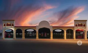 A long, arched storefront with a colorful sunset sky above.