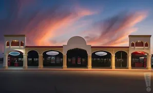 A building with arched entrances under a colorful sunset sky.