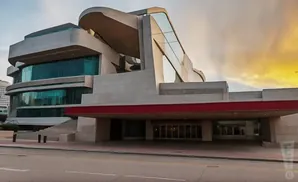 Modern building with sharp angles and glass windows, with a red awning over the entrance.