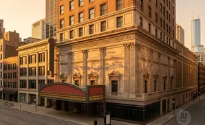 Ornate theater facade with intricate stonework and a marquee, bathed in golden hour light.