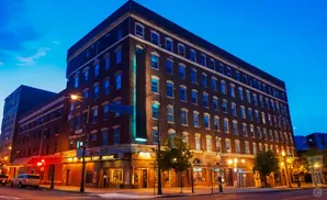 A multi-story brick building with many lit windows at dusk.