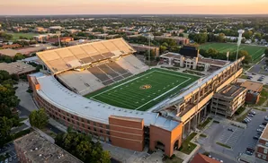 Aerial view of a college football stadium with a green field and brick buildings.
