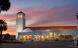 A white building with a tower and orange roof at sunset.