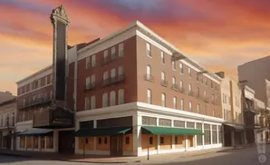A brick building with a large marquee on a street during sunset.