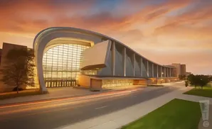 Modern building with curved glass facade at sunset, with light trails from cars on the road.