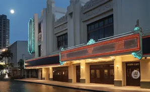 An ornate theater marquee at night with a full moon and city skyline.